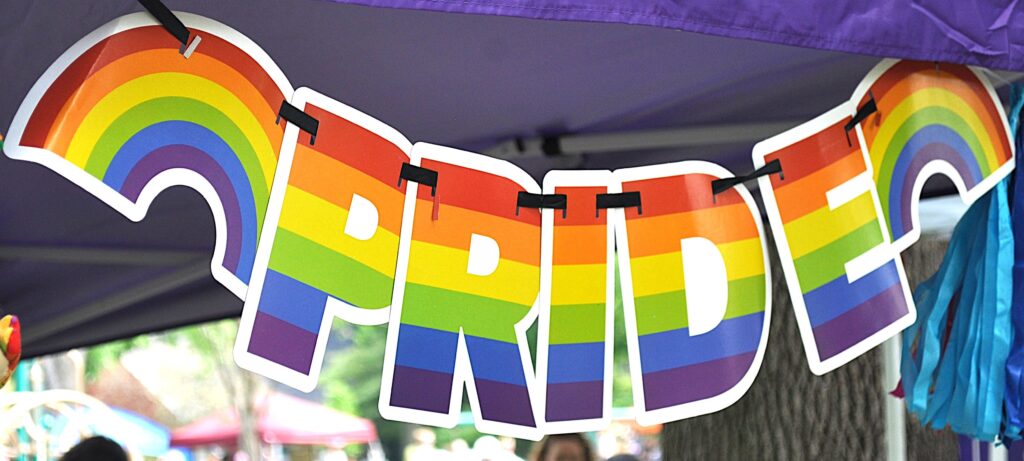 A multi-colored banner reading "PRIDE" hangs from a purple canopy.